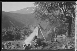Mann på teltur med utsikt mot Gaustatoppen. Pyramidetelt slå