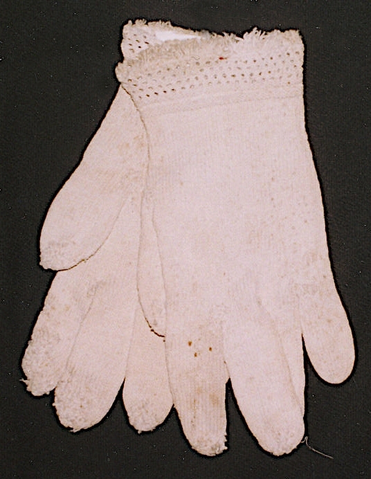 Ett par fingervantar stickade i vitt bomullsgarn, slätstickning, mönsterstickad krage, kort frans av garnet på kragen.
 
Birgitta Blixt 2021.