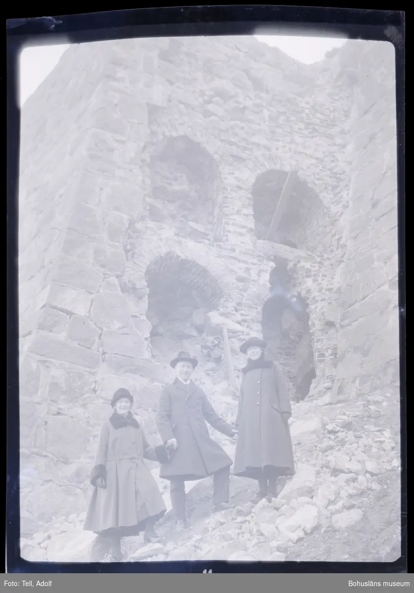 Tre personer ståendes vid en stenruin.