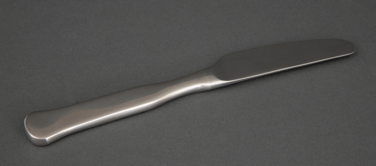 Frokostkniv i presset rustfritt stål med smalt knivblad med små tagger. Skaftet tiltar i bredde og er rett frem til skaftenden som er bredere og avrundet.