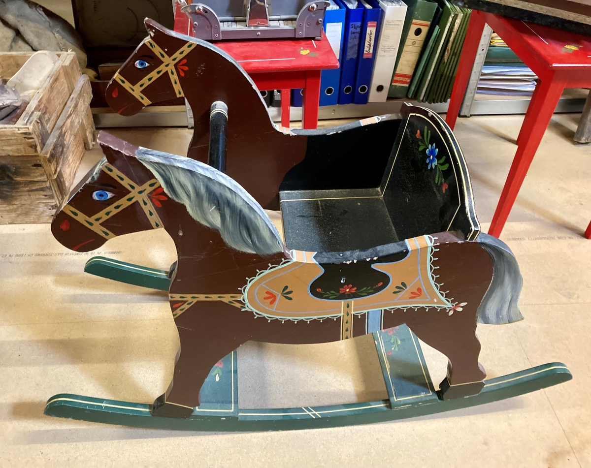 Dobbel gyngehest, utformet som en liten gyngestol med en hest på hver side av setet. Brunmalt og dekorert med påmalte detaljer.