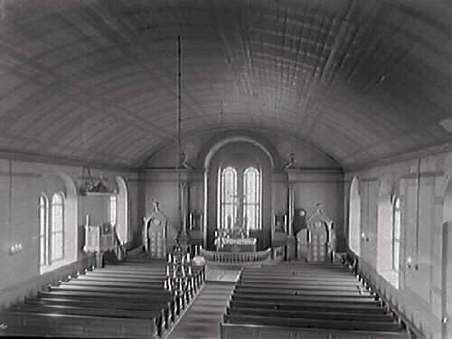 Tvååkers kyrka från omkring 1930, (restaurerades då). Vy från orgelläktaren över kyrkbänkarna mot koret som har två högsmala fönster bakom altaret. Predikstolen sitter på norra sidan. Taket är välvt och har rutig dekormålning. Altargång, altarring, altare, predikstol.