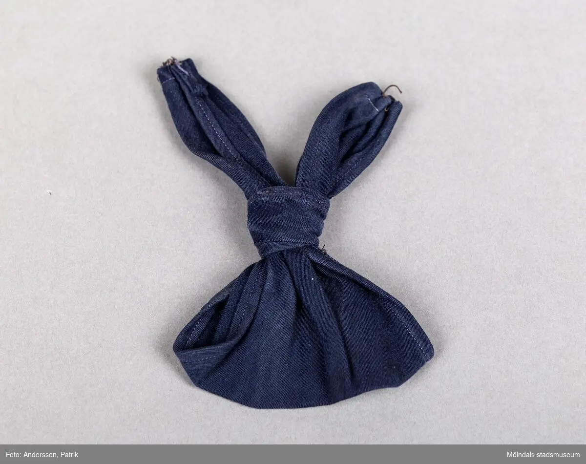 Blå färdigknuten halsduk/slips till sjömansblus (R01096) i barnstorlek. Hyska i den ena snibben att fästa halsduken i blusen med. Blå trådrester i den andra snibben. 
Något fläckig och blekt.