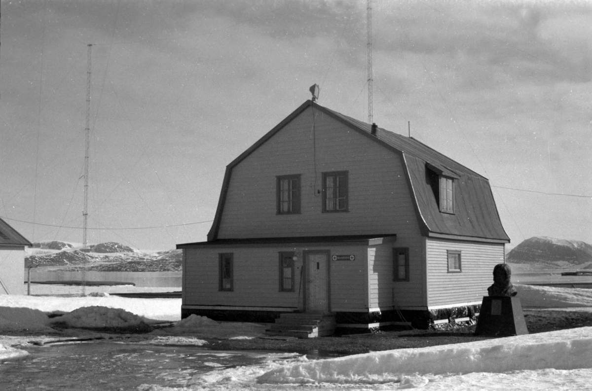Det gule huset i Ny-Ålesund. Amundsens monument ved siden.