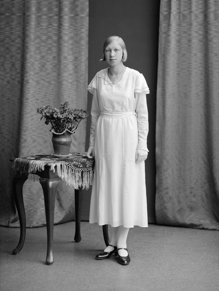 Porträtt av fröken Gerthy Danielsson. Dagen är den 1 juni 1933 och Gerthy har under dagen konfirmerats i Ljung kyrka, ett stenkast från hemmet. Fadern heter Erik Gunnar Danielsson och är trädgårdsmästare vid Ljung slott samt gift med Gerda Helena, född Gustafsson.