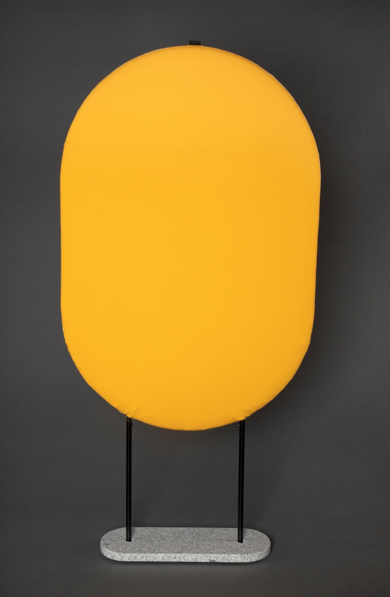 Vertikal oval romdeler i lakkert stålramme med polstret deler kledd med ullstoff, en side mørk gul og en side lys pastell gul.