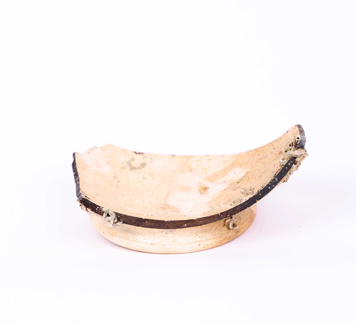 Bunnskår i keramikk, trolig fajanse eller porselen, funnet i Nautasundet, Øygarden kommune. Skåret har delvis avskallet hvit glasur.