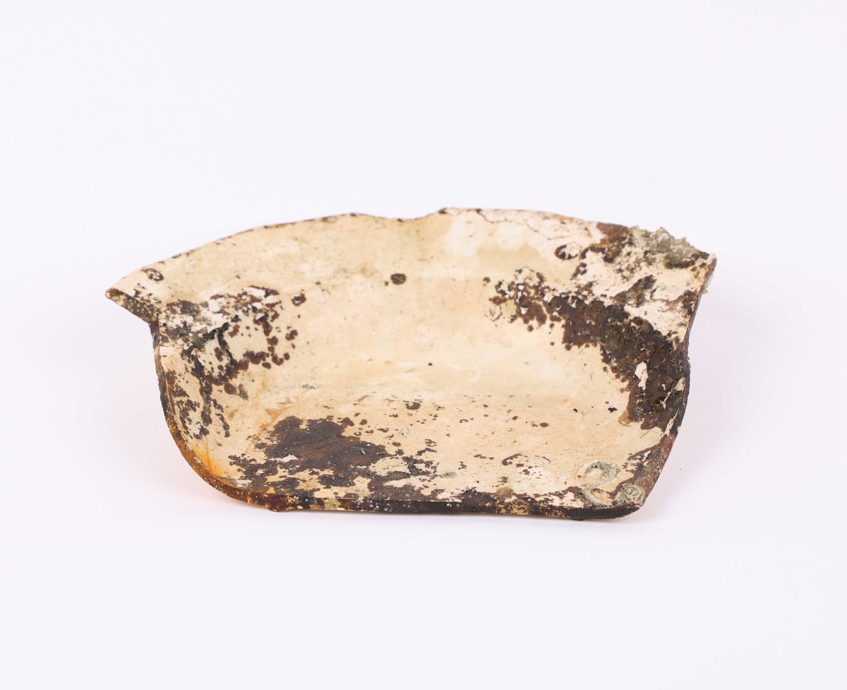 Bunnskår i keramikk, trolig fajanse eller porselen, funnet i Nautasundet, Øygarden kommune. Skåret har delvis avskallet hvit glasur.
