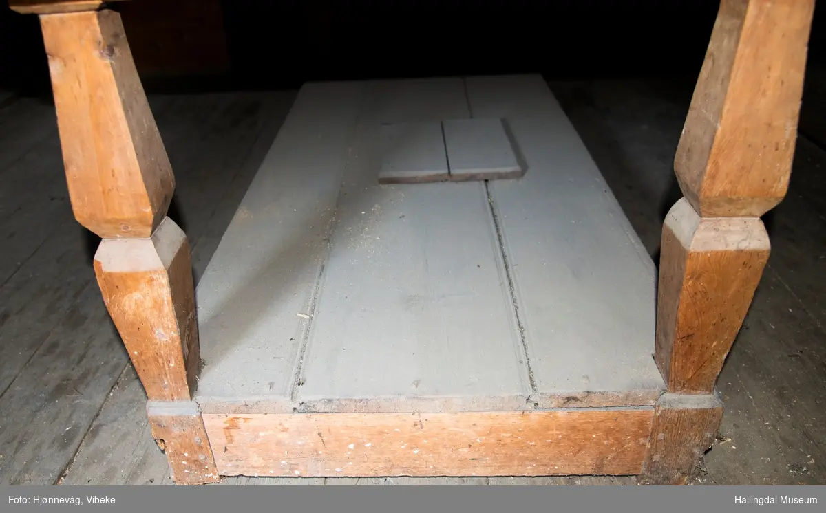 Langbord lagd av tre planker. Bordet ligger oppå et understell med 4 bein som er festet inni en karm med planker oppe og nederst. Nederst er det lagt 3 profilerte planker og det dannes et rom mot gulvet som er 16 cm høyt. Midt i plata (de tre plankene) er det en luke som kan løftes av. Det er skjært ut 4 firkantete hull i bordplata som en løs karming kan settes ned i. Karmen består av 4 "grove" føtter med 2 planker på langsidene og 3 planker på kortsidene. Den er rødmalt.