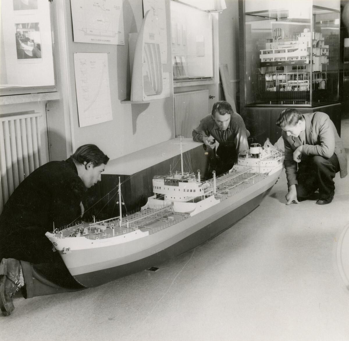 Utställning i Sjöfartsavdelningen, avdelning för Nyare varv. Tre unga män tittar på fartygsmodellen SVEADROTT.