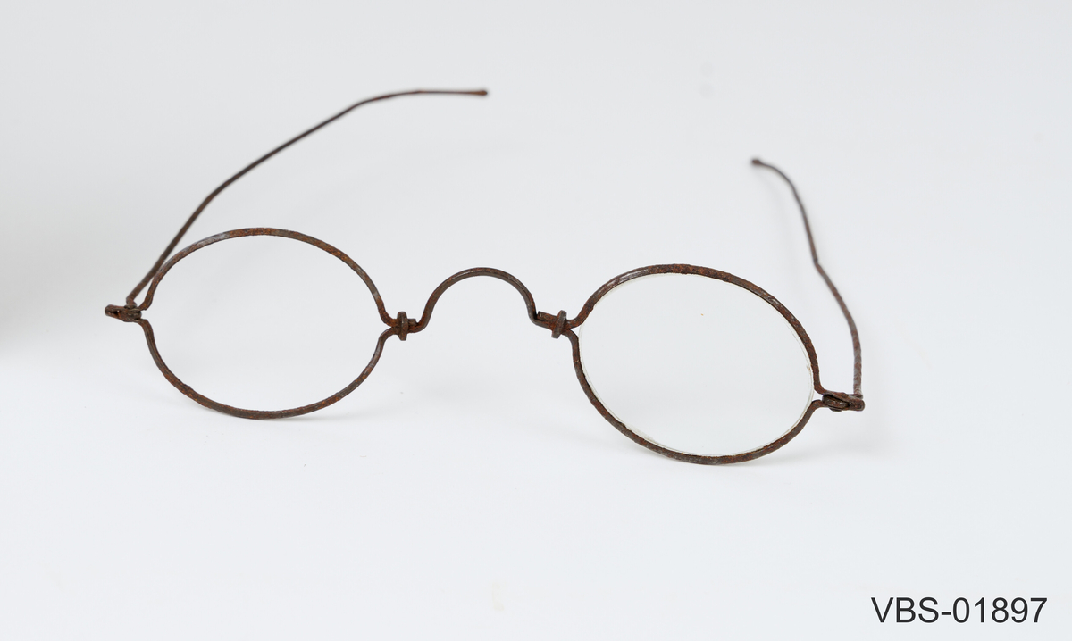 Leddet innfatning med to stenger som kan brettes sammen/ strekkes ut. 
Tilnærmet smal, oval utformet front med tilpasset brilleglass.

