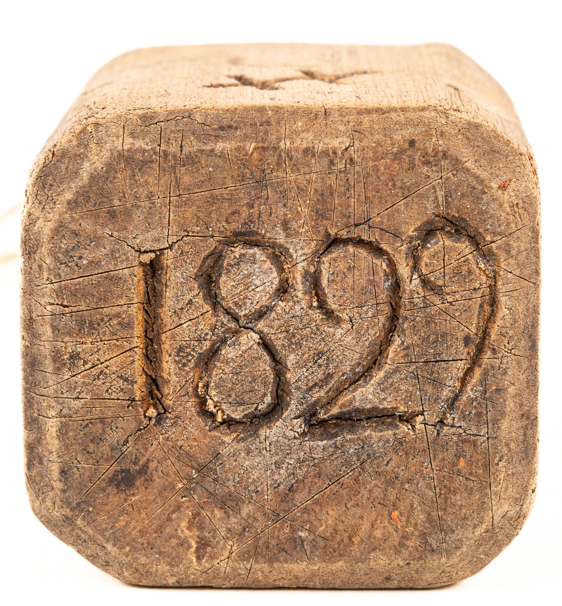 Plogklubba av trä, fyrsidig med handtag och inristade bomärken. Daterad 1829.
