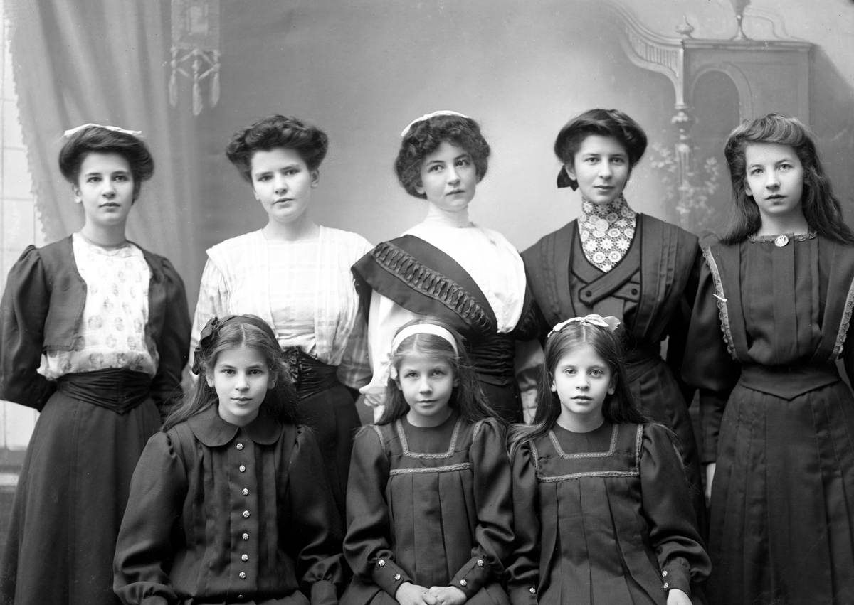 Anton Sundelius 8 döttrar framför Karl Nyströms kamera i ateljén i Klara. I främre raden: Aina, Elsa-Britta och Helmi och i övre raden: Ethel, Märta, Ebba, Vivi och Elly.  Bilden togs kanske i samband med faderns 50-årsdag år 1908