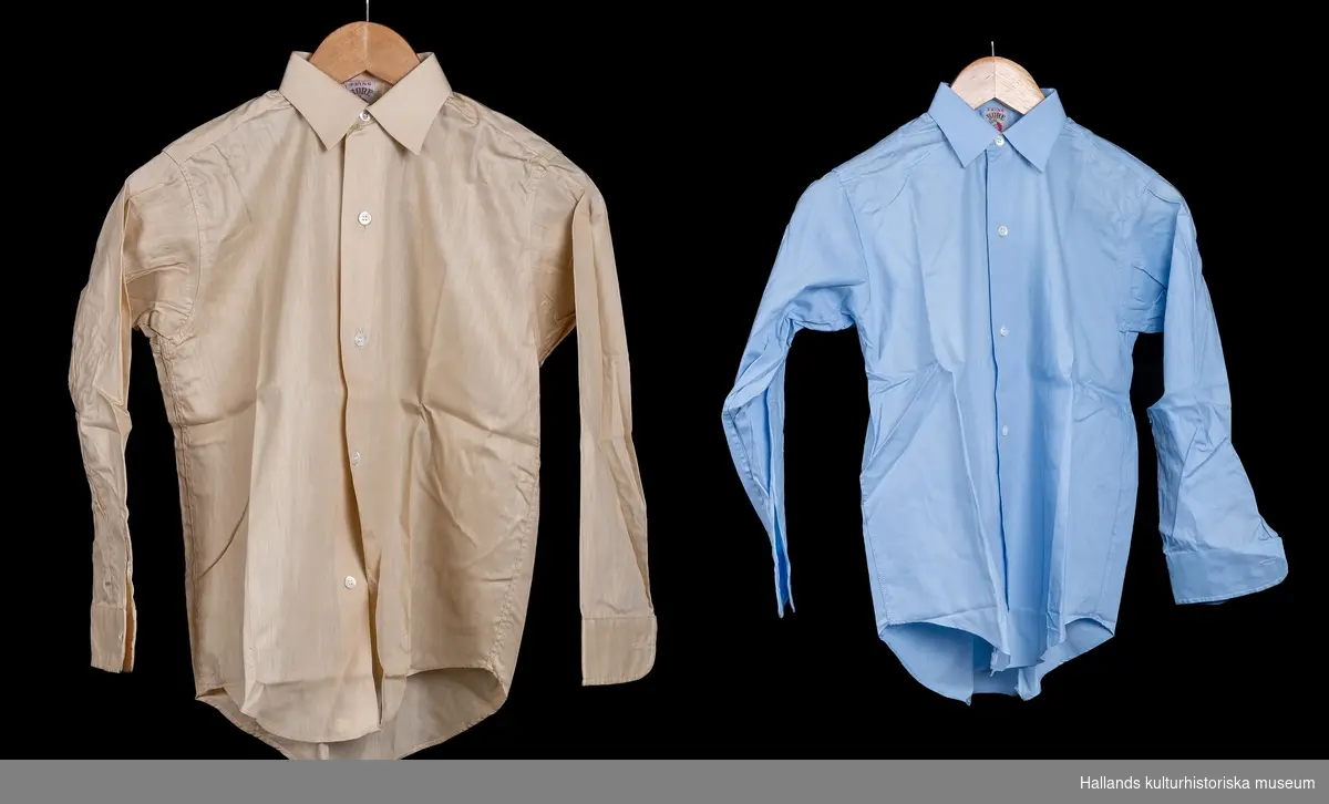 Skjorta avsedd för pojke. a) Ljusblå bomull. Rak modell med knäppning fram. Märkt: "Prins Bore storlek 31. Kokas ej, stärkes eller strykes fuktig". b) Beige bomull. Rak modell med knäppning fram. Märkt: "Prins Bore storlek 31, kokas ej, stärkes eller strykes fuktig". c) Stödkartong av papp, överkroppsformad. Boreskjortan med bättre passform.d) Stödkartong av papp, rektangulär form med upphöjt stöd för kragen. e) Skjortkartong med lock, rektangulär form. Märkt: "Aktiebolaget Melka skjortor". a) Längd 66 cm. Bredd 38 cm. b) Längd 66 cm. Bredd 38cm. c) Längd 29,5 cm. Bredd 21 cm.d) Längd 29,5 cm. Bredd 20,7 cm.e) Längd 34 cm. Bredd 22,5 cm.