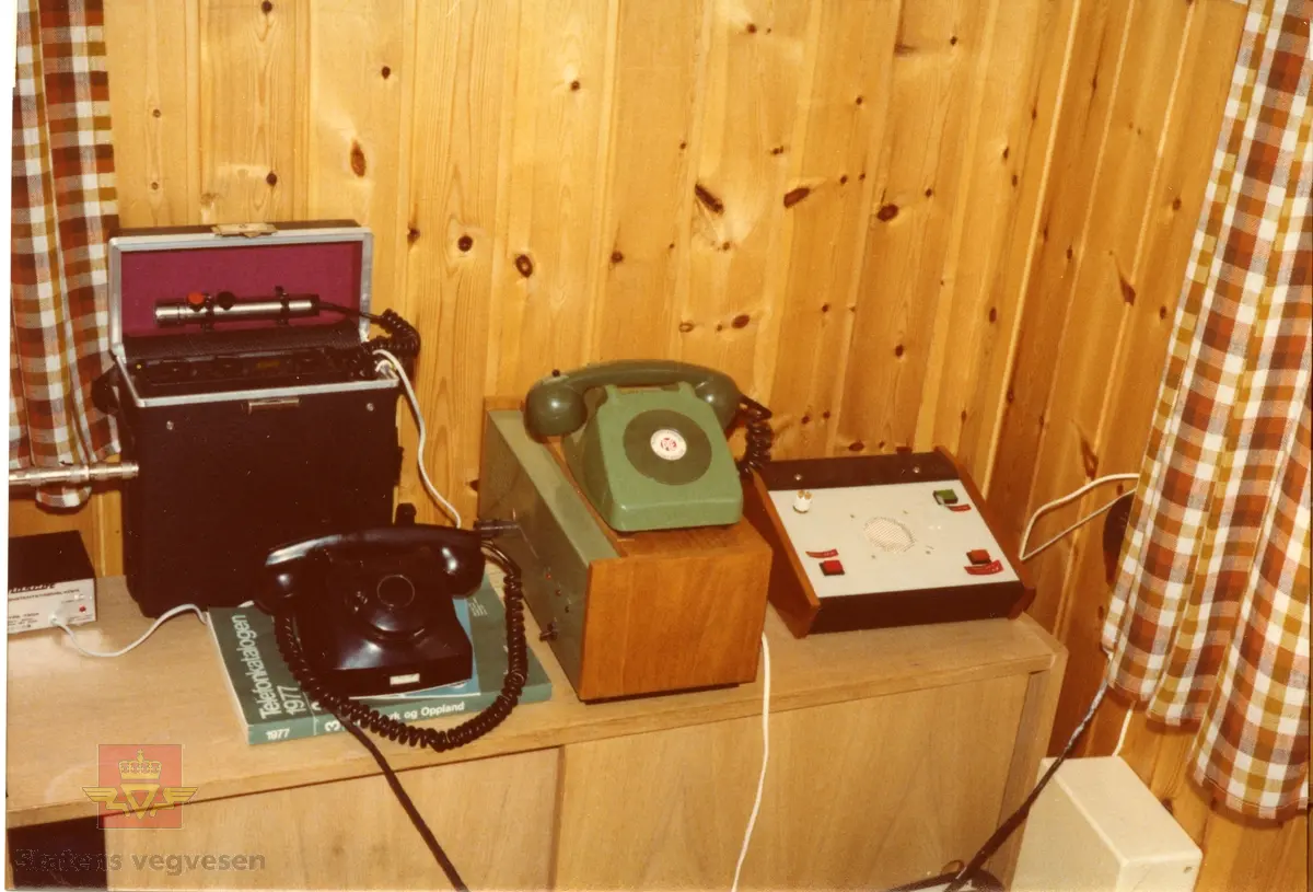 Bildet er fra Dombås vegstasjon. Fra venstre står det en styrestasjon med en telefon foran. Under den grønne telefonen står det en styrestasjon. 
Den grønne telefonen er til styrestasjonen. Til høyre ser vi et apparat til styring av linjevalg. Opplysninger fra Vegkontoret i Lillehammer.