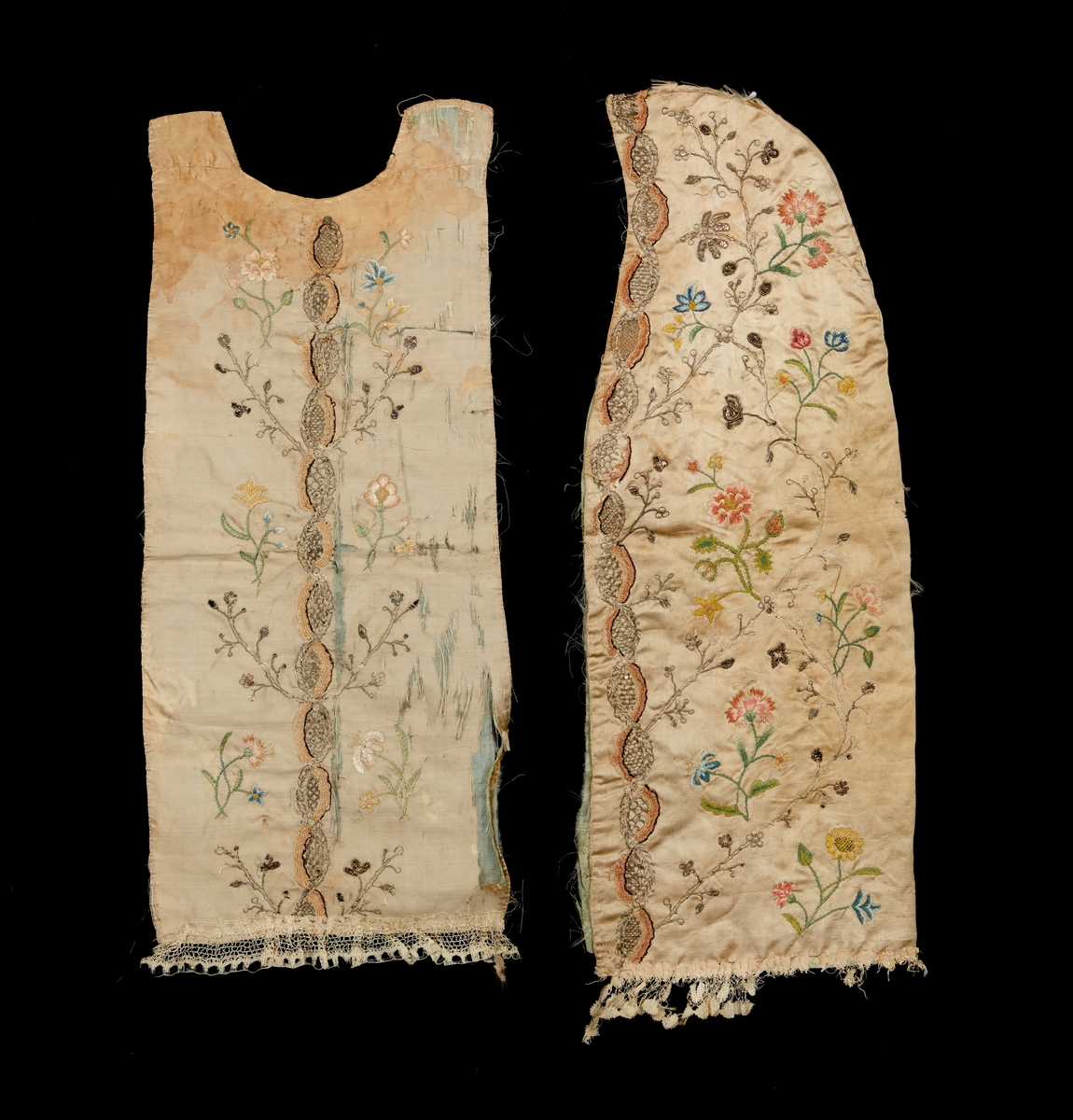 Dopklänning i två delar, från Kalmartrakten. Täcke och långt kläde för ryggsida och huvud. Av ljusgrått siden. Broderad med silvertråd, paljetter samt silke med blomstermotiv. Nedtill prydd med silkesspets.