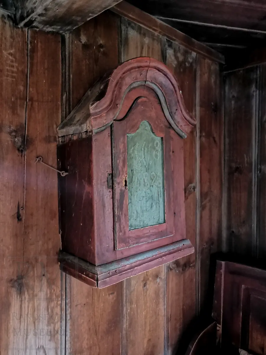 En dør. To innvendig hyller. Buet profilert toppstykke. Dør med grønnmalt speil.