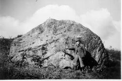 Arthur Tennvassås står ved en stor stein som blir kalt for B