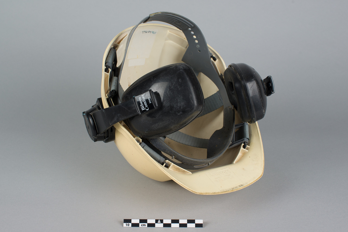 Hjelm påmontert hørselvern. Pålimt bilde av Pluto bak. Hjelmen ble brukt av Knut Mølderup som jobbet med vedlikehold, ABT.