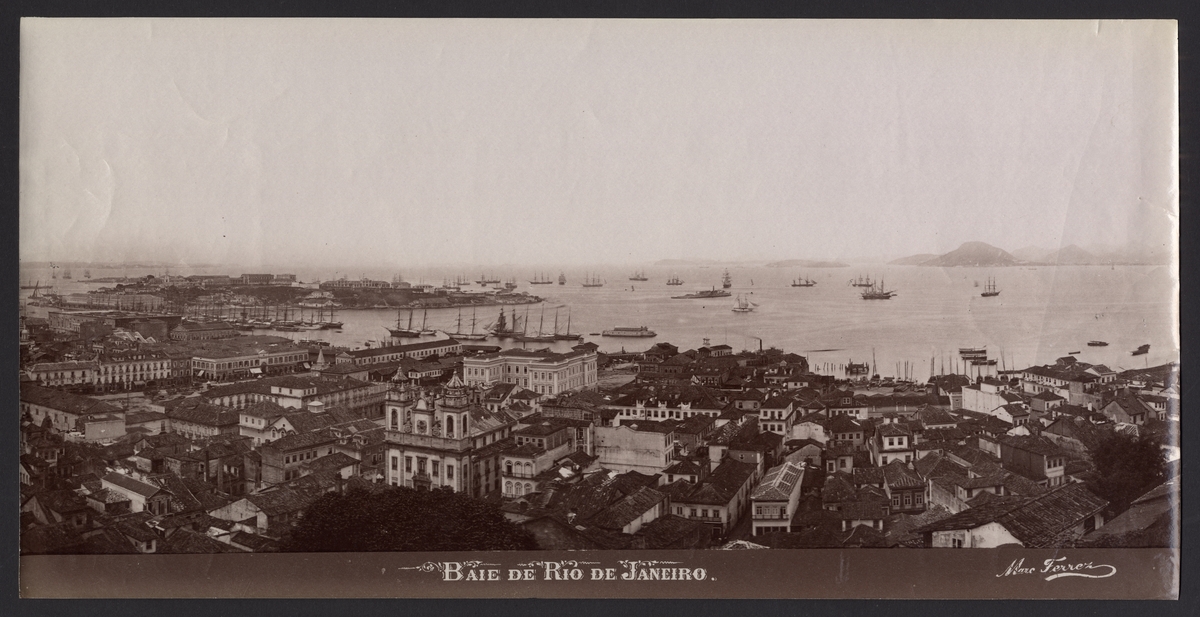 Bilden föreställer en vy över viken Baie de Rio de Janeiro med staden i förgrunden och redden med många segelfartyg i bakgrunden.