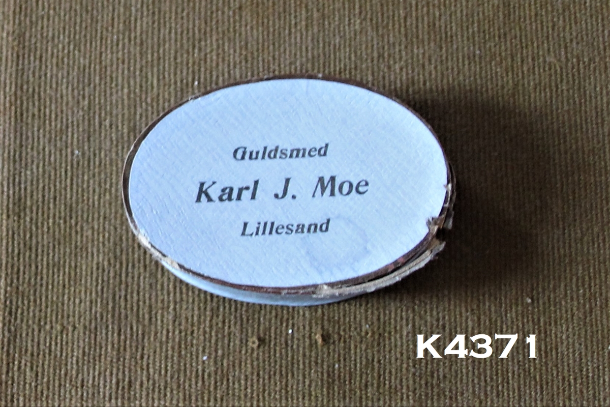 Eske:
Oval. Lyseblå. "Gull" kanter. Gullsmed Karl J. Moe, bor i Lillesand.