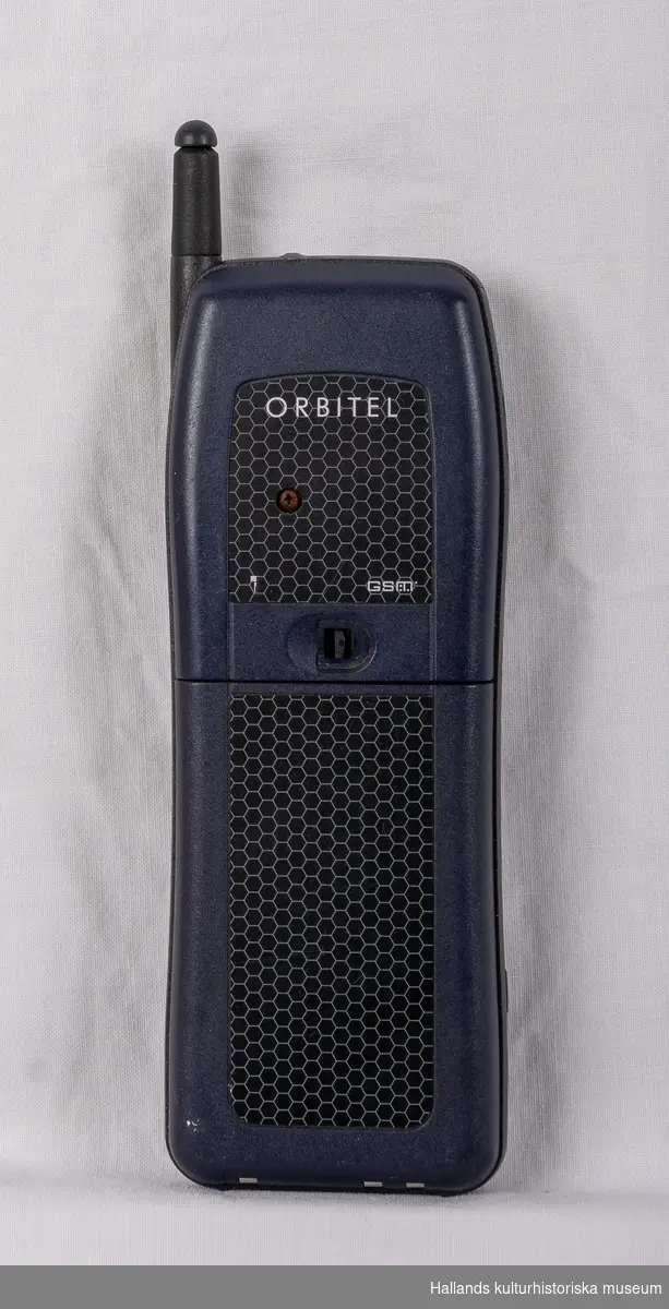 Orbitel 902 (Tillverkare: Orbitel, modell: 902) med yttre skal av svart och marinblå hårdplast. På framsidan finns en digital skärm, en gummerad knappsats, högtalare, mikrofon, samt tillverkarens logotyp: "Orbitel". Telefonen har en utfällbar pinnformad antenn. På baksidan av telefonen sitter ett batteri som löper utmed drygt halva telefonens längd. Även märkning: "Orbitel", "GSM". På telefonens undersida en kontakt under lucka.