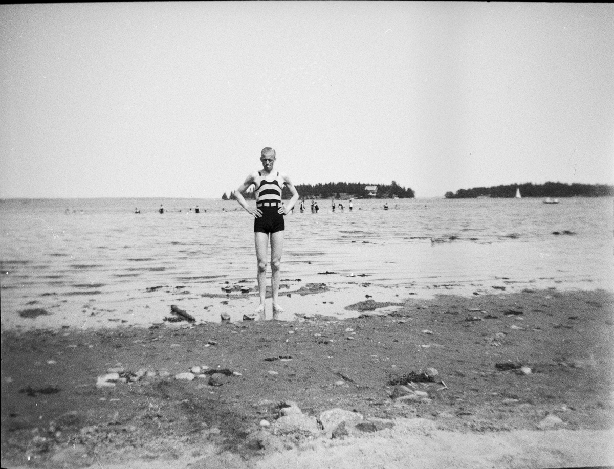 En man i baddräkt står på badstrand, Gräddö, Uppland