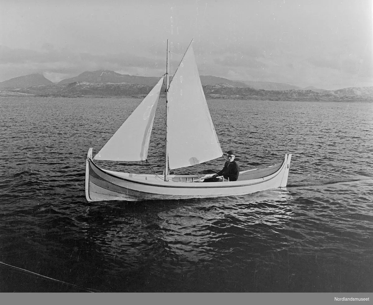 Bildet viser en ny Bindalsbåt utenfor Bodøsjøen. Eieren er lektor Hans Holand, han sitter i båten. I bakgrunnen ses Straumøya og Børvasstindene.