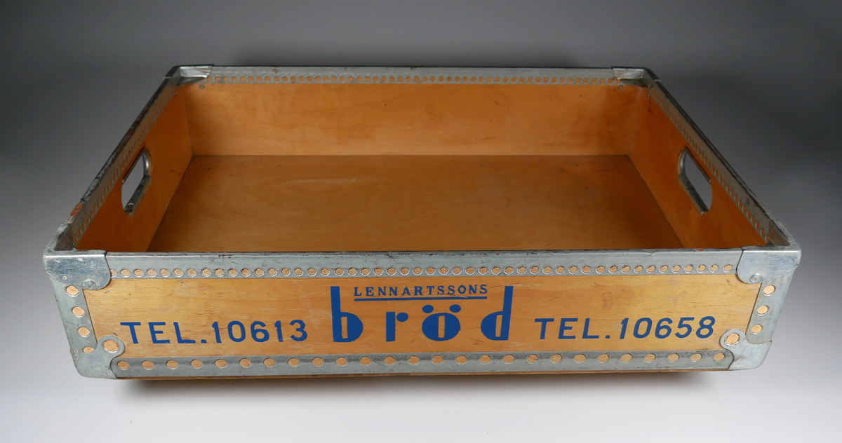 Låda för transport av bröd från Lennartssons bageri. Lådan är tillverkad i trä och metall av företaget Plywood produkt. Kom till givaren via Motorförarnas helnykterhetsförbunds klubblokal i Bälinge skola.