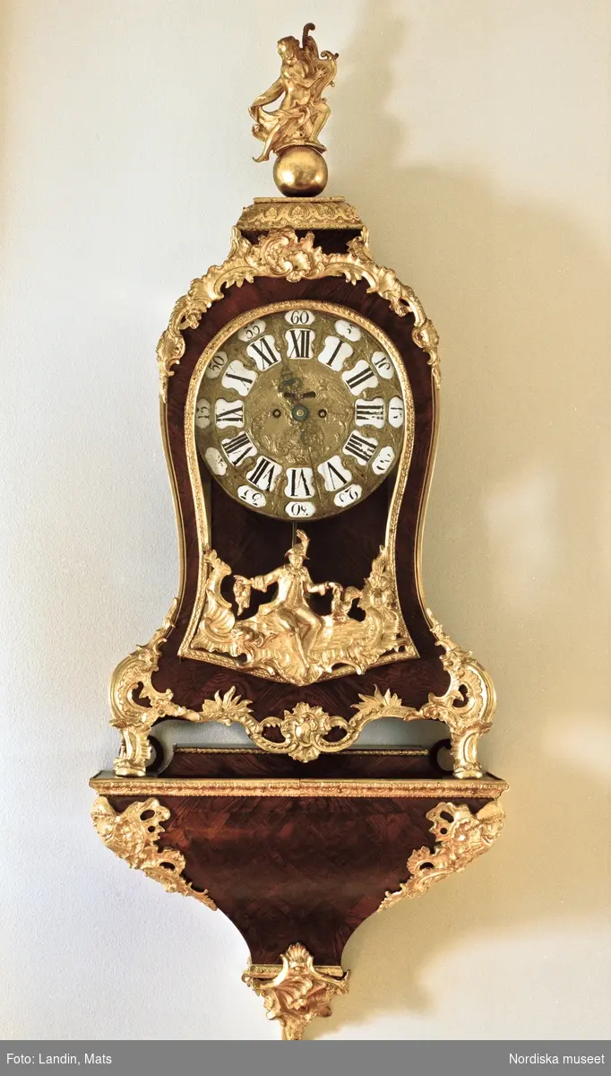 Franskt ur på konsol, på krönet spelar Apollo på sin lyra. Urverket signerat "Förfärdigat af Joh: Erl: Schmack, priviligierad uhr=fabriqeur, Stockholm, No 33" (1745-62).