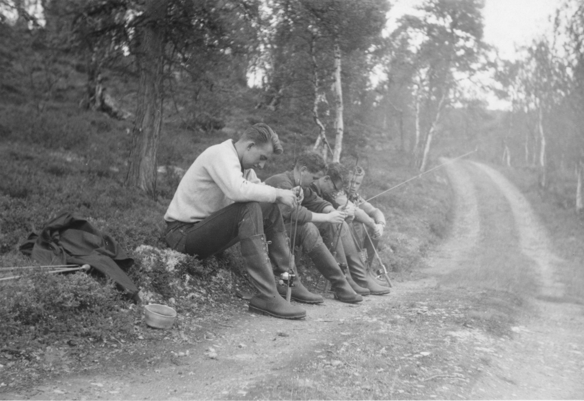 Fire unge menn med fiskestang tar en pust i bakken. Gjerdrum ca 1952.