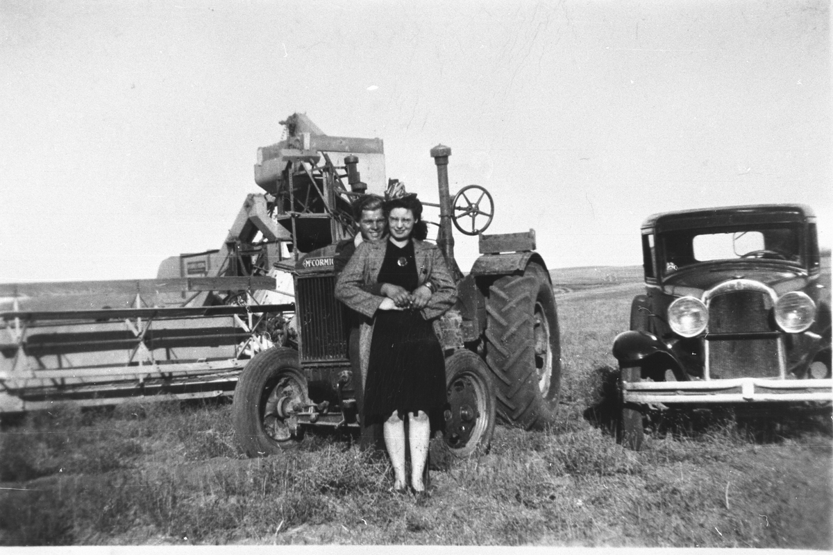 Mann og dame framfor traktor (McCormick) og bil