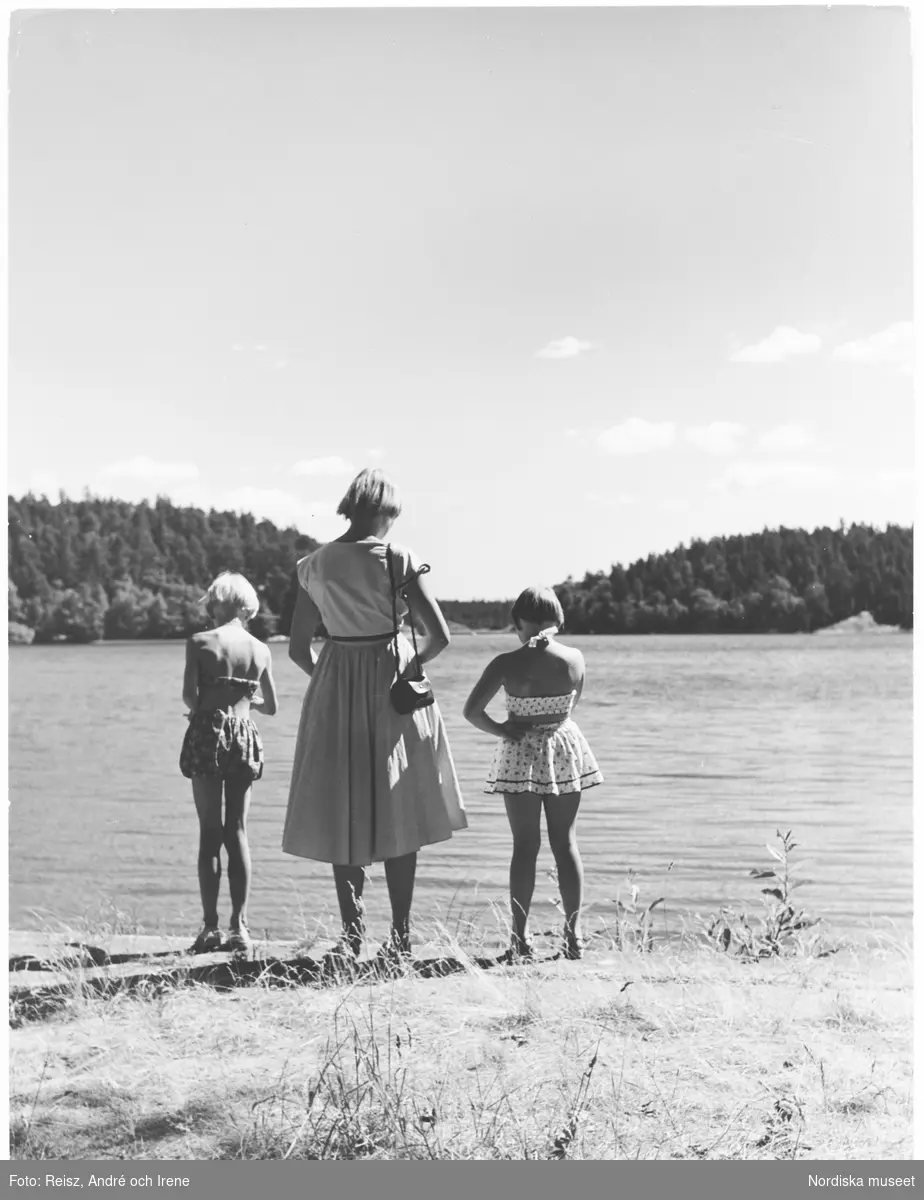 En kvinna med sina två flickor skådar utöver Mälaren vid Drottningholm.