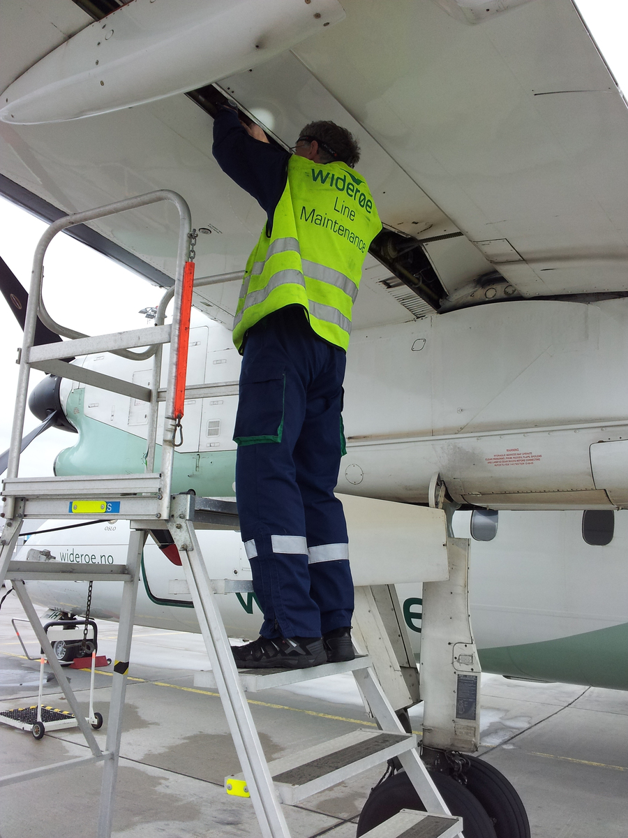 En av Widerøes flyteknikere sjekker om det er spor etter drivstofflekkasjer på en Dash 8.
