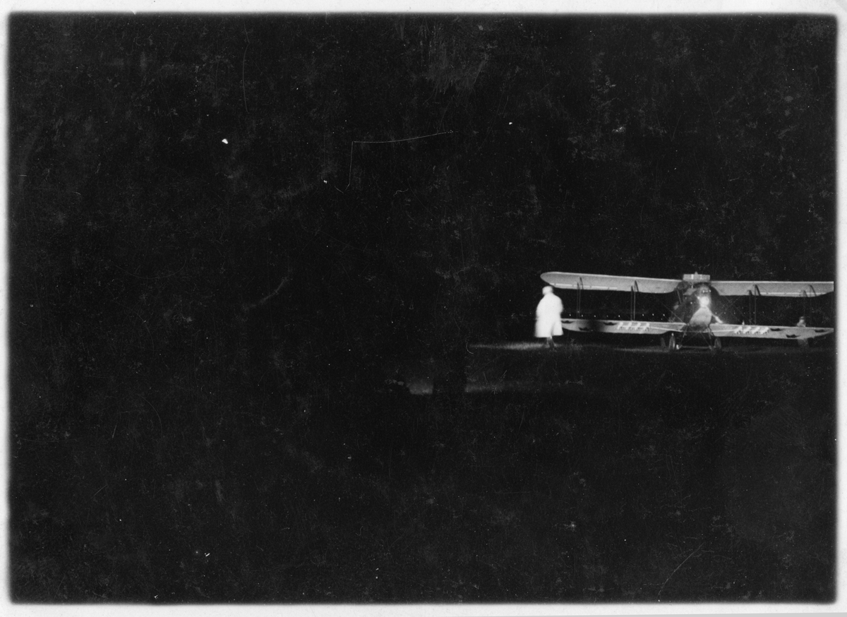 Nattflygning i Rinkaby, 1925.
Klargöring av militärt flygplan på flygfält inför mörkerflygning för Flygkompaniet. En man vid flygplanet.