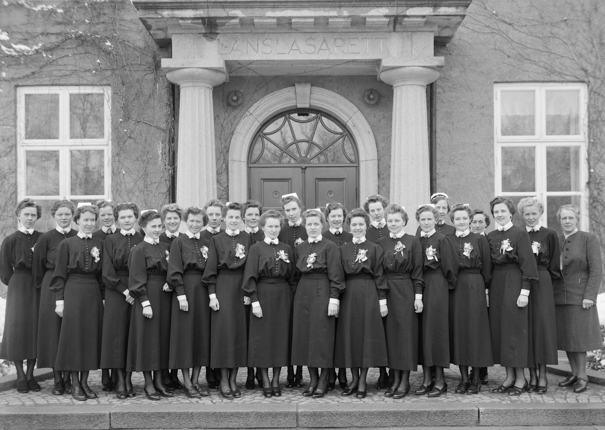 Examensbild från Birgittaskolan i Linköping. De nybakade sjuksköterskorna står uppställda framför huvudentrén till Linköpings länslasarett. Året är 1944.