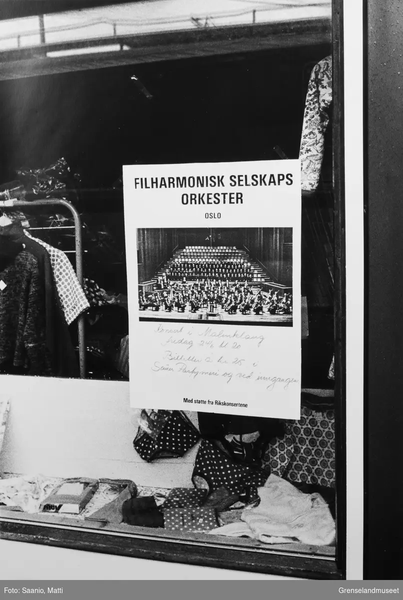 Bilde tatt i Bugøynes på 80-tallet. Plakat i vindu på butikken til Berg om Filharmonisk konsert på Malmklang i Kirkenes.