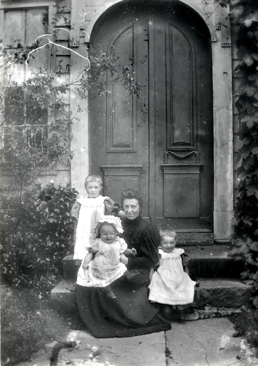 Kvinne med tre barn på trappen utenfor Krohnstedet.