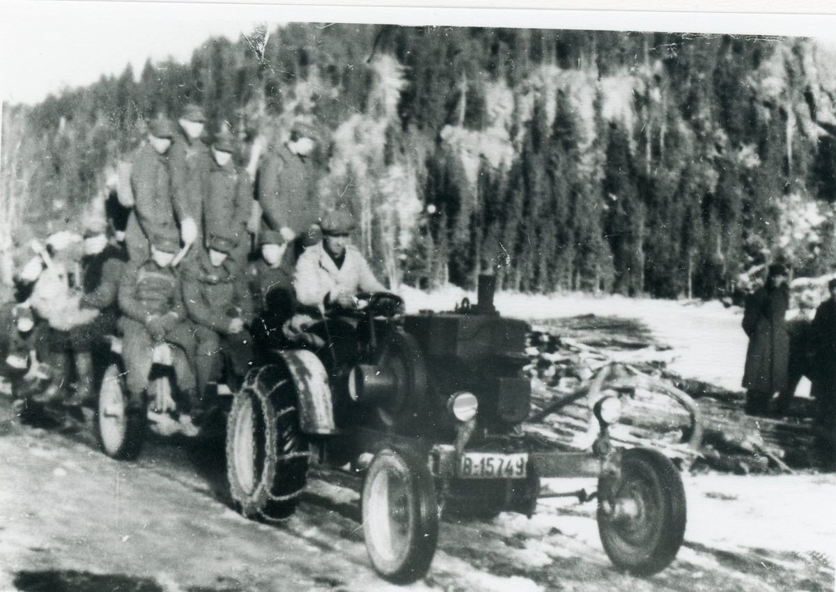 Traktor (B-15749) med tilhenger som persontransport. Mange med militær uniform
