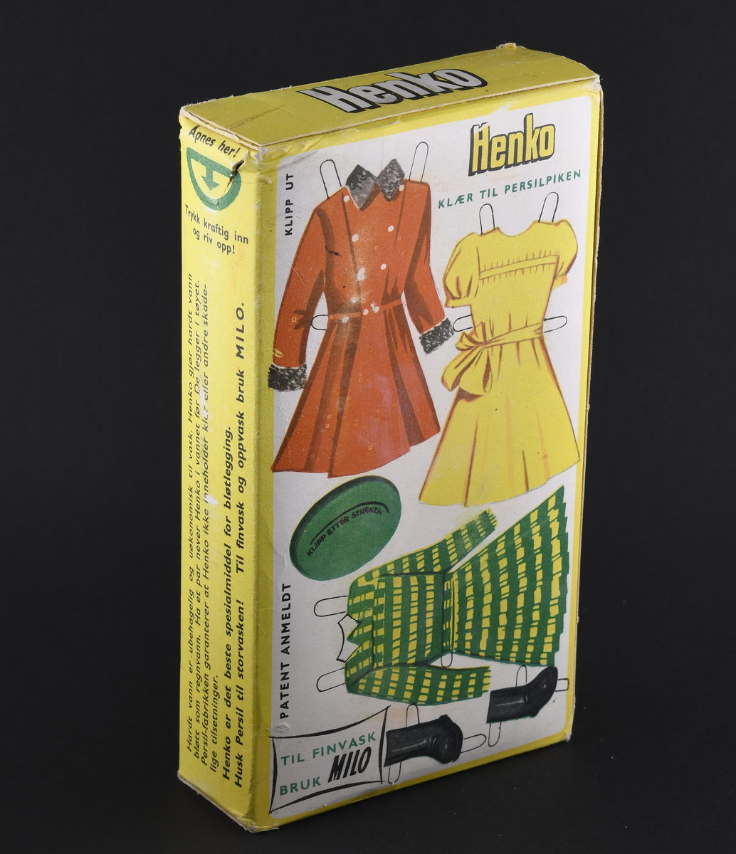 En pakke med vaskepulver. Original emballasje av papp. Pakken har stående rektangulær form og har gul grunnfarge. På baksiden er utklippbare klær for å sette på Persilpiken.