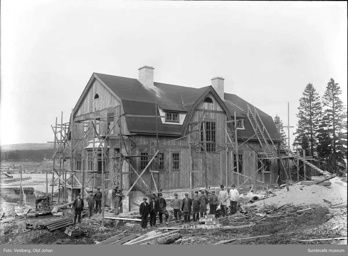 Två bilder av ett pågående husbygge i Essvik, byggnadsarbetarna står uppradade framför huset som ursprungligen var disponentbostad kopplat till Nyhamns fabrik. Nuvarande (2024) adress är Kontorsvägen 16.