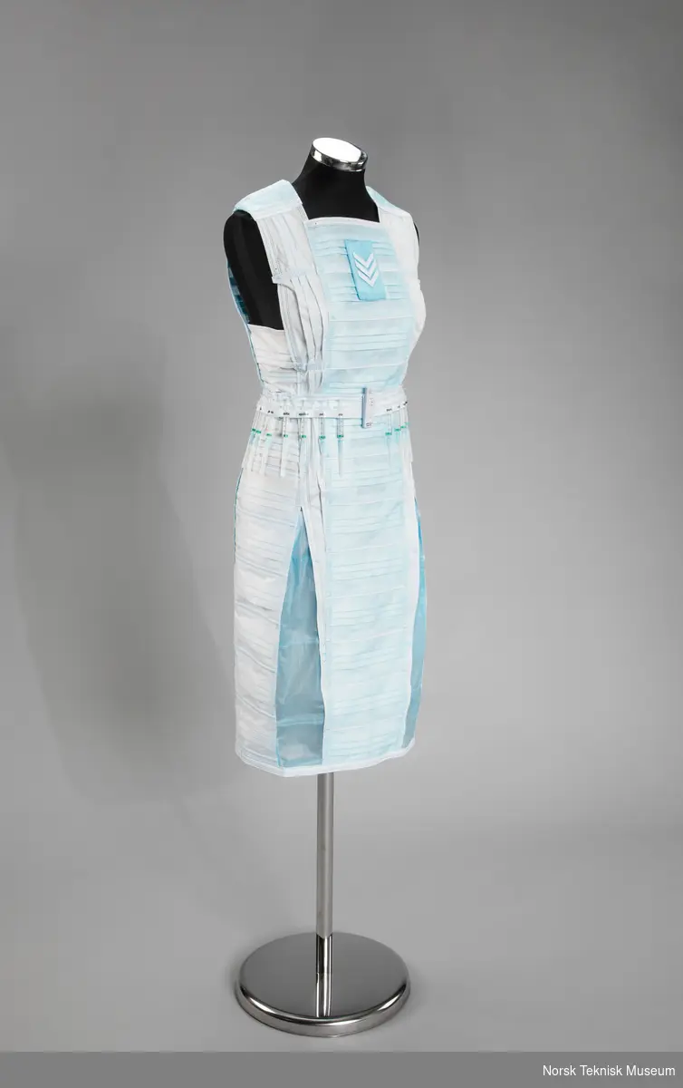 Kjole laget av munnbind på kjolestativ. Kjolen har et belte laget av vaksinesprøyter og en koronatest, med greske bokstaver for å representere stammer av koronavirus.