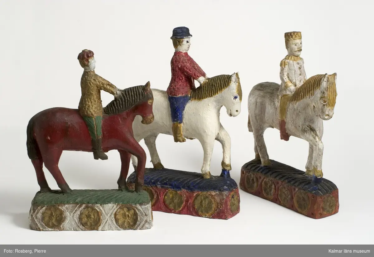 KLM 12928. Skulptur, träskulptur. Skulptur i form av en manlig ryttare på en häst. Ryttaren och hästen bemålad i vitt, gult och rött. Hästen står på en sockel bemålad i rött, gult och blått. Titel: Faraos ryttare.