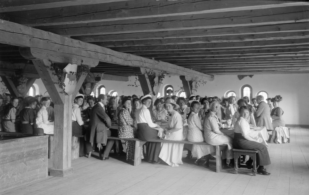 Motiv från kvinnligt studentmöte i Bjärka Säby 1912. På bilden har studenterna satt sig till bords i godsets magasinsbyggnad.