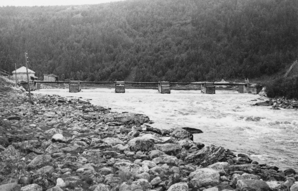 Olstappdammen i Vinstravassdraget i Nord-Fron i Oppland, fotografert i 1936. Bildet er tatt i motstrøms retning fra en posisjon på den sørøstre sida av elvløpet. Dammen besto av seks steinfylte tømmerkister, plassert på linje, på tvers av elveløpet, med mellomliggende bruer. Da dette fotografiet ble tatt sto alle de fem damløpene åpne. Når dammen skulle magasinere vann for fløtinga i den nedenforliggende delen av Vinstra, ble damløpene stengt ved hjelp av «nåler». Dette var planker som ble stukket ned i vannet på motstøms side av dambruene, slik at de ble stående, tett i tett, som en vegg, med terskelstokker på elvebotnen og dambruene som anleggspunkter.
