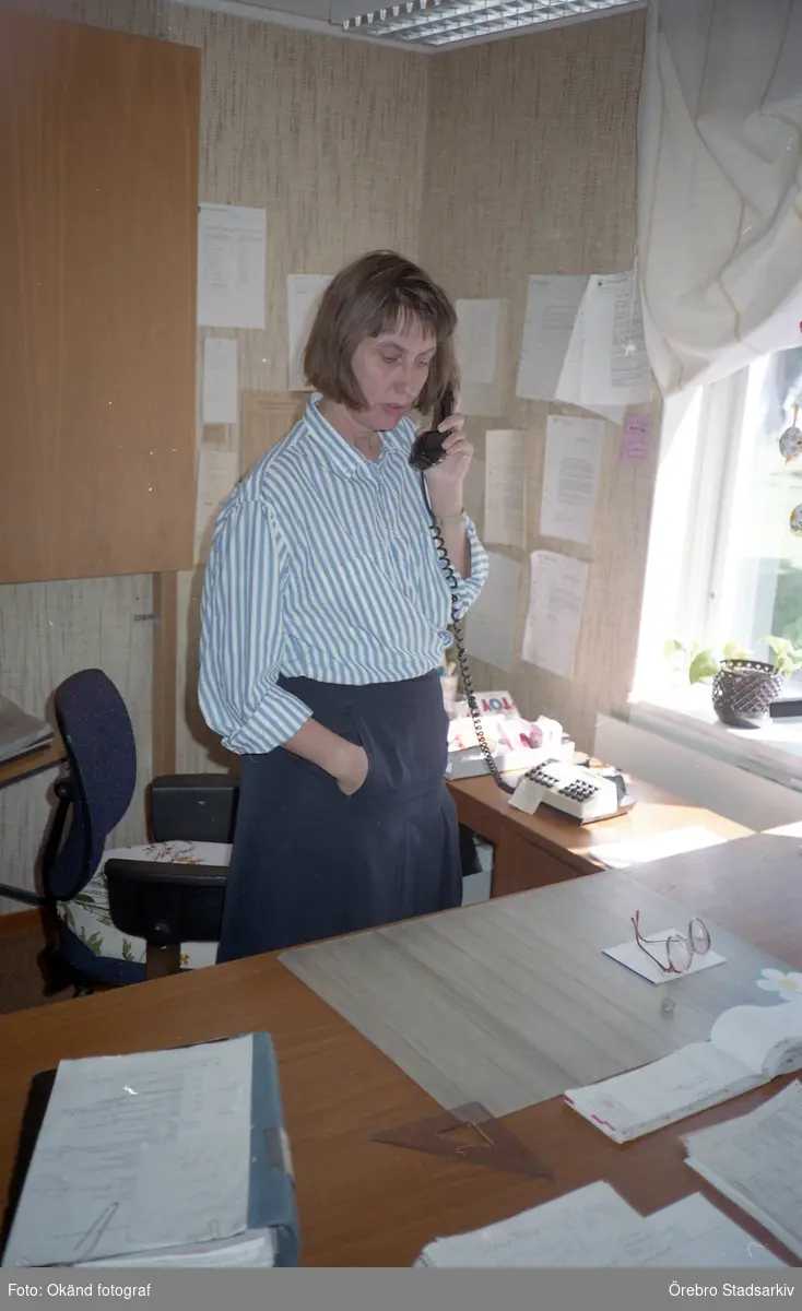 Kvinna talar i telefon vid skrivbord