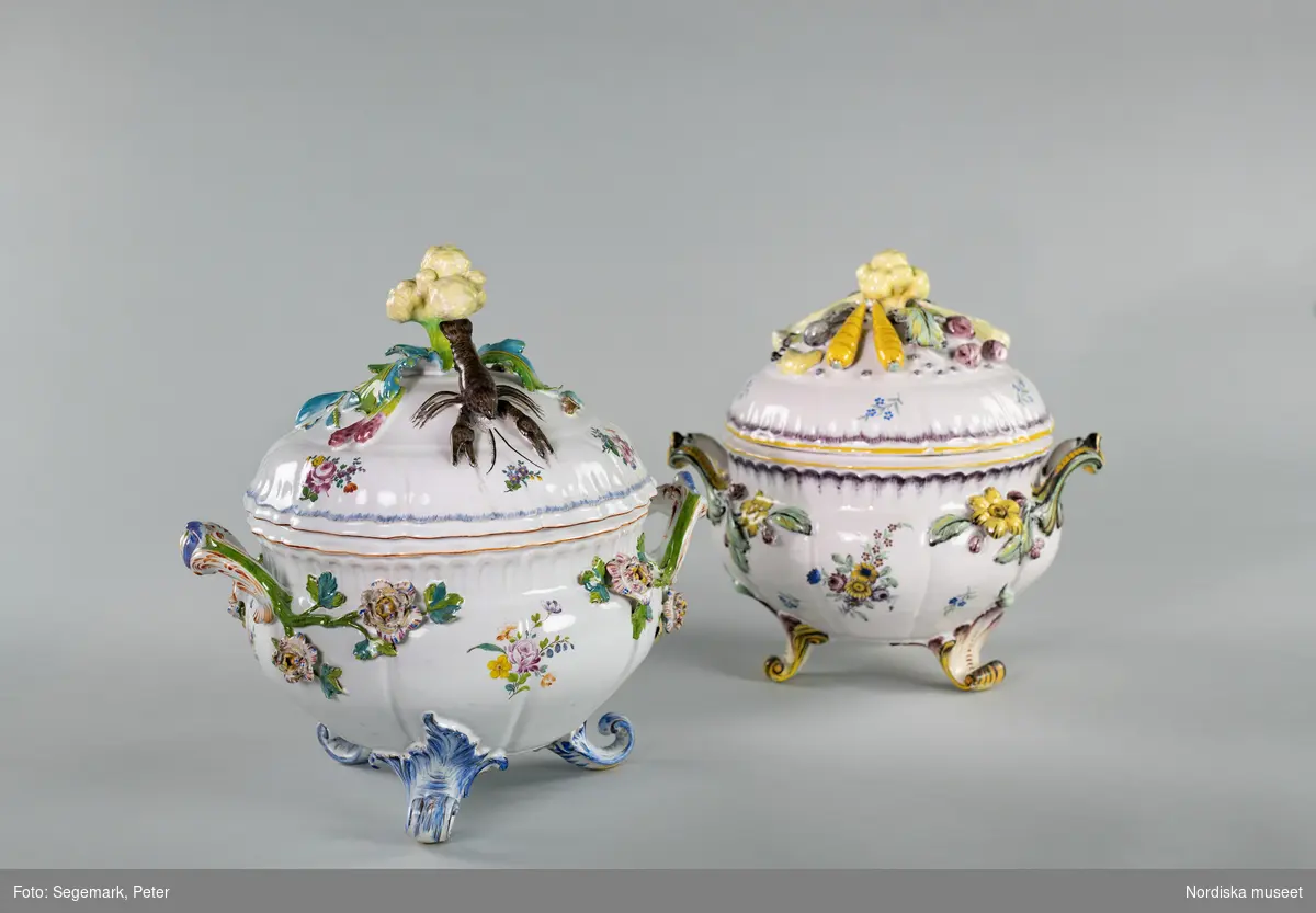 Två soppterriner av fajans tillverkade vid Rörstrand 1759 respektive 1771. Plastisk dekor i form av växter, grönsaker, rotfrukter och kräfta. Målade blommor.