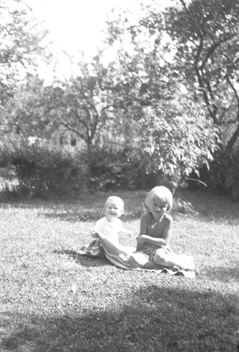 Lena och Berit Sundling på filt i trädgård.
