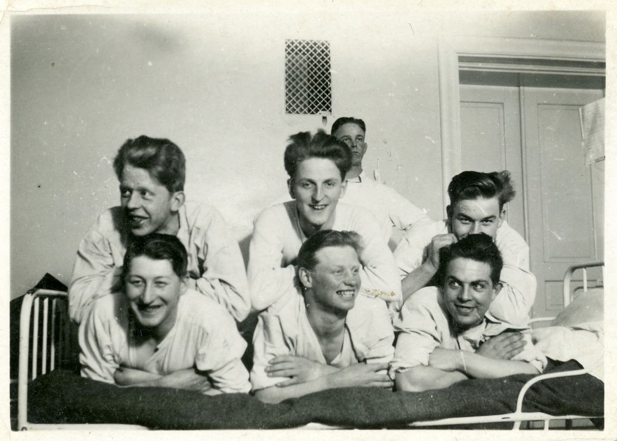 Harald Sundling [övre Raden i mitten] tillsammans med fem andra unga män poserar för kameran, i bakgrunden ytligare en ung man.