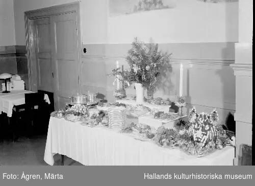 Julbord med garnerat grishuvud på källaren Munken i Stadshotellet, Varberg. Bild 2 visar ett par kvinnor ur personalen vid matsalens julgran.